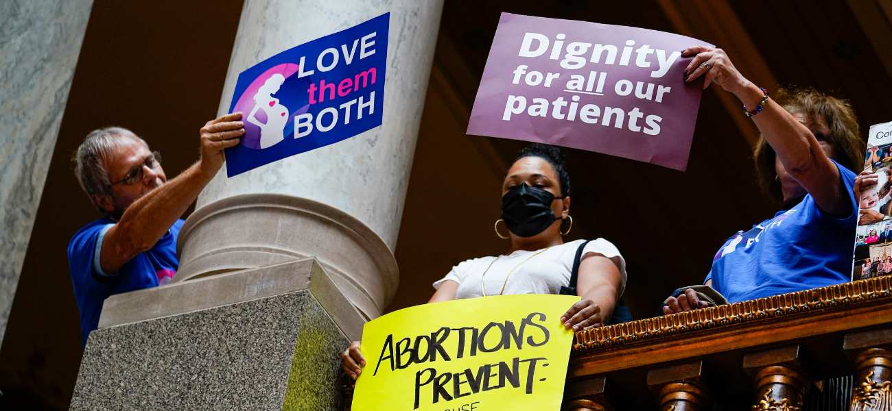 Anti-abortion supporters try to cover a sign of an abortion rights supporter during an anti-abortion rally as the Indiana Senate Rules Committee met a Republican proposal to ban nearly all abortions in the state during a hearing at the Statehouse in Indianapolis, Tuesday, July 26, 2022. (AP Photo/Michael Conroy)