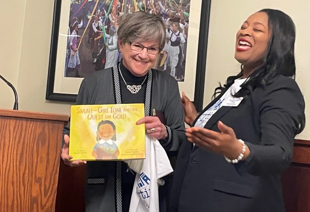 Prisca Barnes (right), president/CEO of Storytime Village, Inc., provides Gov. Laura Kelly with a children's book during a Literacy Day event at the Statehouse.