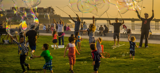 Children play with bubbles near a beach in this stock photograph.
